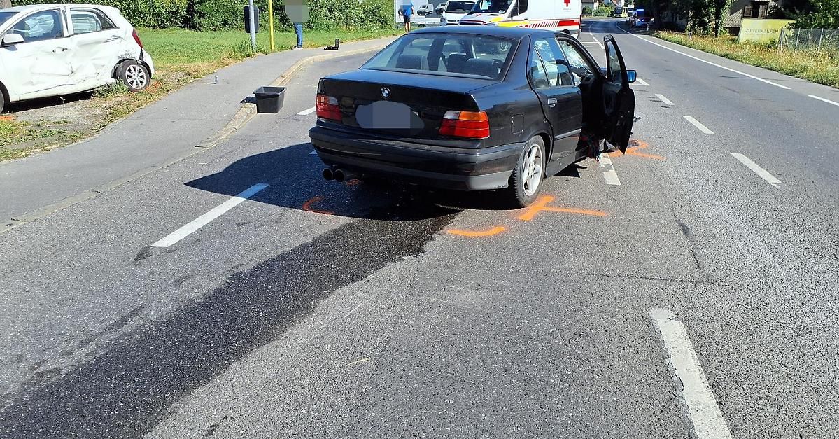A black BMW car with its back door open is parked on the side of the road, with orange markings and a trash bin nearby.