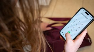 Eine Person hält ein Telefon mit einem grünen Knopf auf dem Bildschirm, möglicherweise in einem Anruf.
