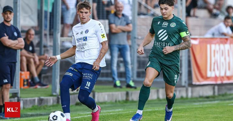 Two soccer players in action on a field. One in white and blue, the other in green, both running and looking at the ball.