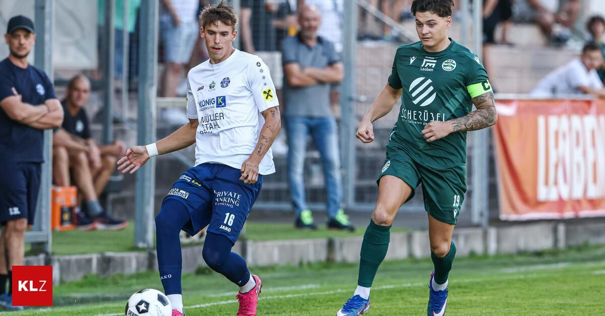 Two soccer players in action on a field. One in white and blue, the other in green, both running and looking at the ball.