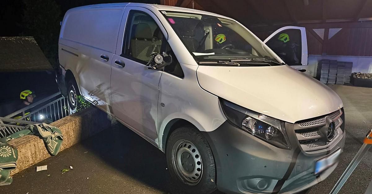 A white Mercedes-Benz van with a broken windshield and a damaged front bumper is parked in a dark area.