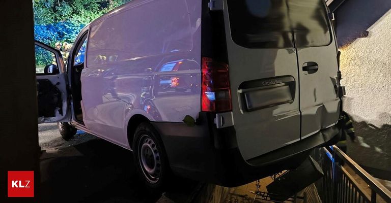 The back of a white Mercedes-Benz van with its door open, parked in a dimly lit area at night.