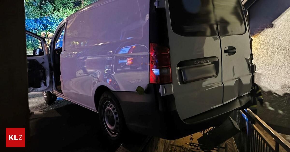The back of a white Mercedes-Benz van with its door open, parked in a dimly lit area at night.