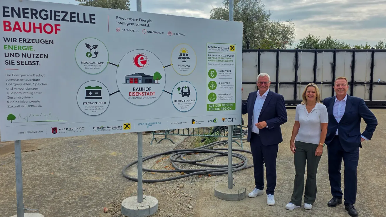 A man stands next to a large signboard with various icons and text related to energy sustainability, including solar panels, wind turbines, and eco-friendly practices.