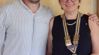 Ein Mann und eine Frau stehen nah beieinander und lächeln. Die Frau trägt eine blau-gelbe Schärpe mit dem Wort Präsident darauf.