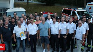 Eine Gruppe von Feuerwehrleuten und Freiwilligen posiert für ein Foto vor Rettungsfahrzeugen.