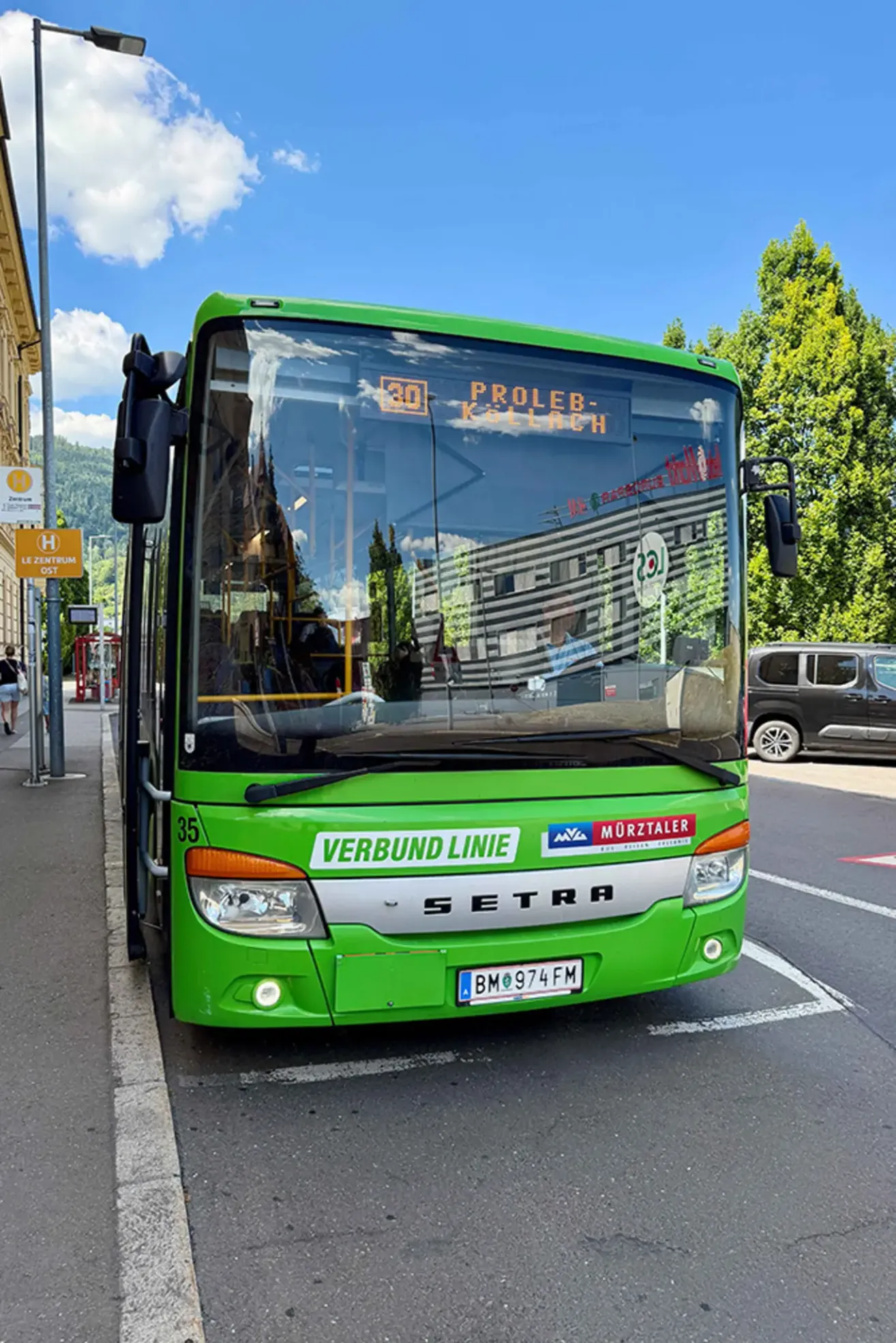 A green bus with the text 'VERBUND LINIE' and 'SETRA' parked on the side of the road.