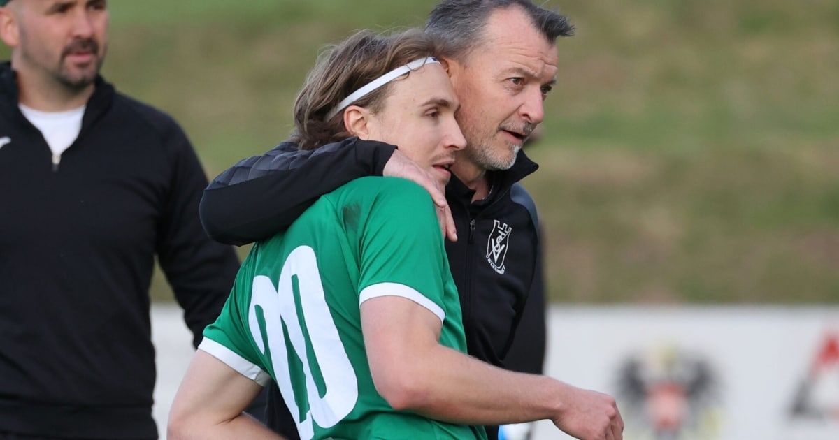 Ein Fußballtrainer umarmt einen Spieler in einem grünen Trikot mit der Nummer 10, beide mit ernsten Gesichtern.