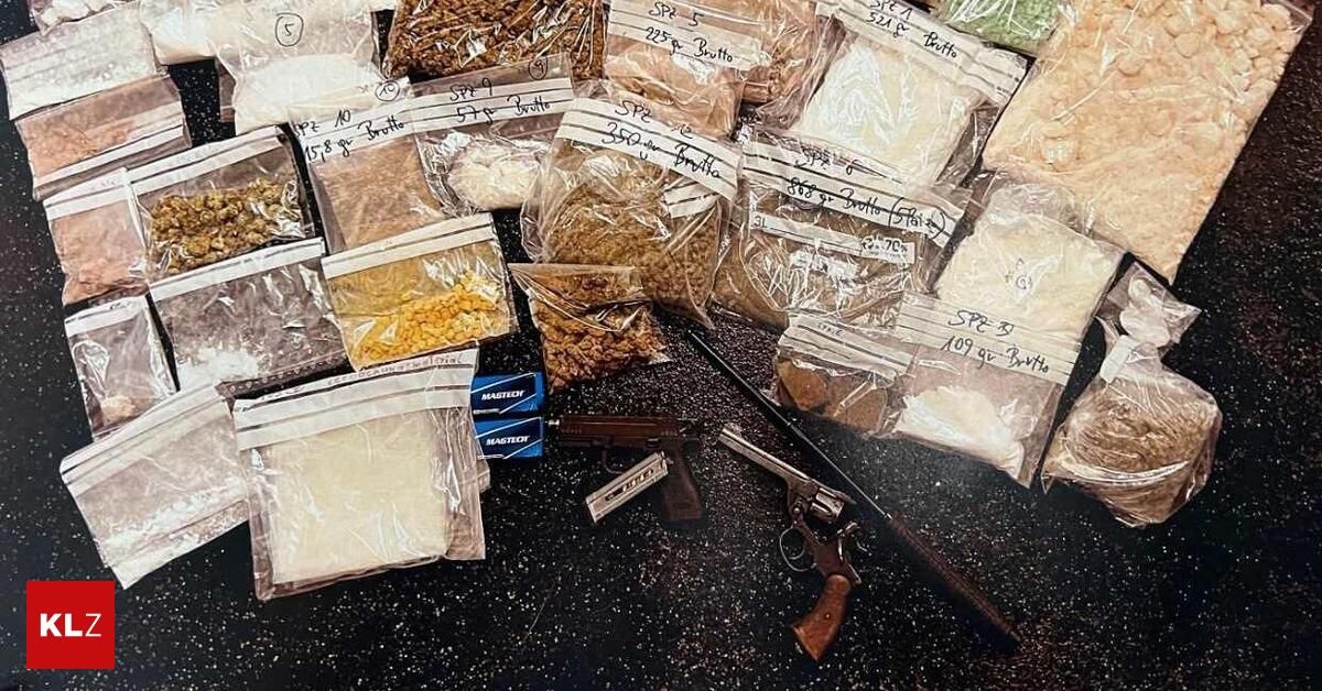 A collection of various items including plastic bags with different powders, a box of cigarettes, and two firearms on a black surface.
