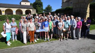 Eine Gruppe älterer Menschen posiert für ein Foto vor einem historischen Gebäude. Sie tragen alle Sonnenbrillen und einige halten Gehstöcke.