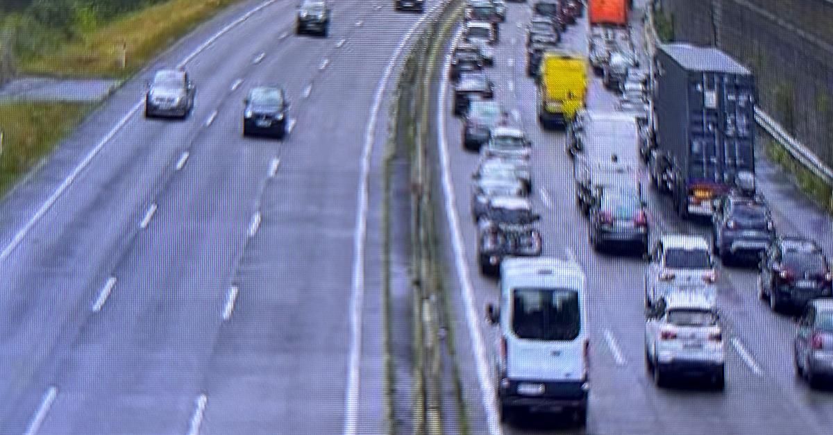 A busy highway with multiple lanes of traffic, including cars, trucks, and vans, moving slowly due to congestion.