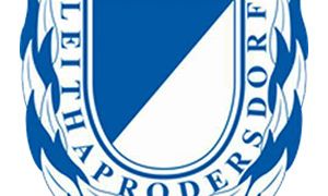 Das blau-weiße Logo von SV Leithaprodersdorf zeigt einen Schild mit einem weißen Dreieck in der Mitte, umgeben von blauen Flammen und Lorbeerblättern.