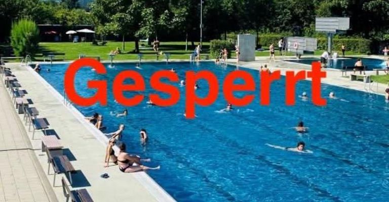 Eine Gruppe von Menschen schwimmt in einem großen Freibad, wobei das Wort Gesperrt in Rot über das Wasser geschrieben ist.