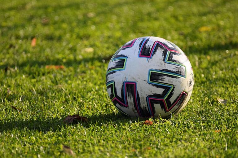 Ein Fußball mit einem weißen und schwarzen Design liegt auf einem Rasenfeld.