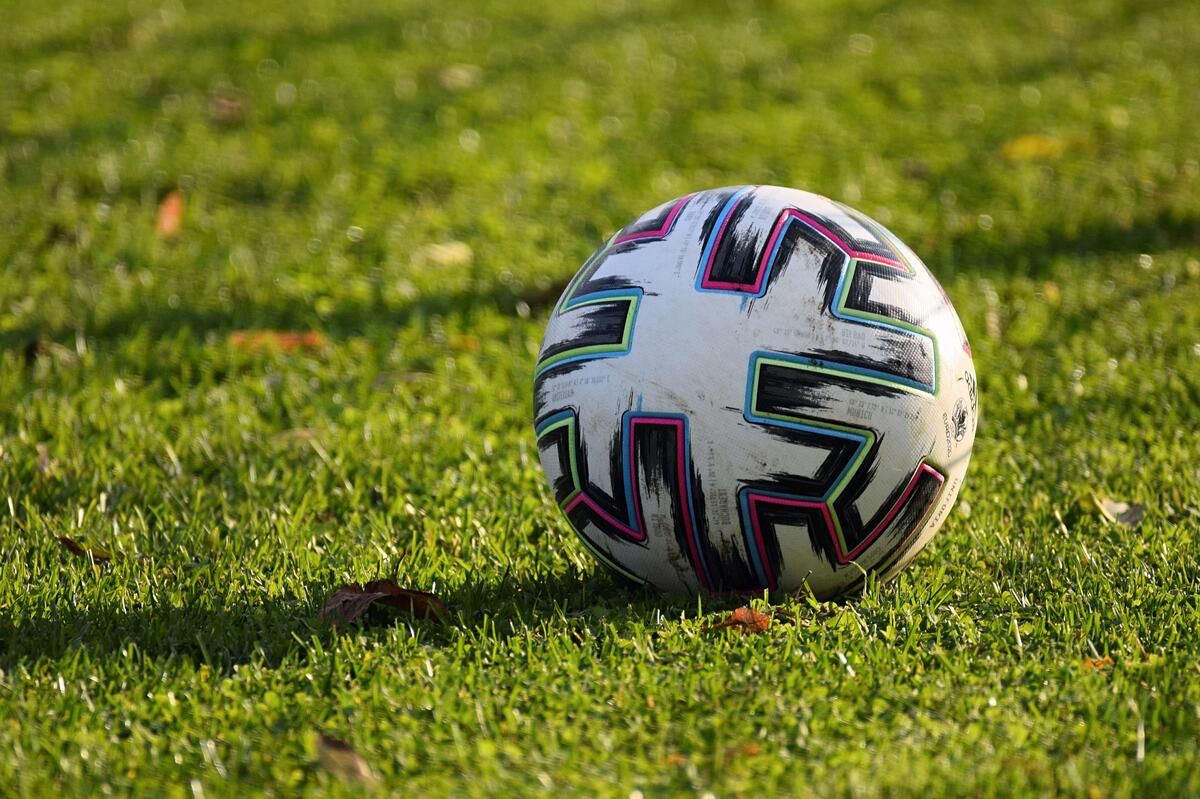 Ein Fußball mit einem weißen und schwarzen Design liegt auf einem Rasenfeld.