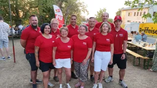 Eine Gruppe von Menschen in roten T-Shirts mit den Buchstaben SPO darauf posiert für ein Foto in einer Außenumgebung.