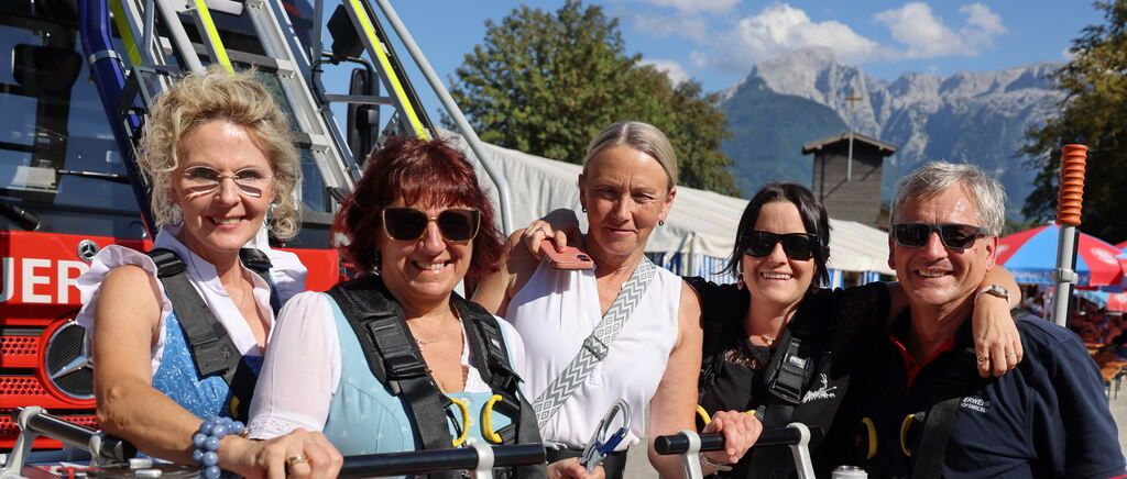 Eine Gruppe von Menschen mit Gurten und Sonnenbrillen, die lächelnd und posierend für ein Foto vor einer Bergkette stehen.