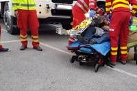 Rettungskräfte transportieren eine verletzte Person auf einer Trage von einem Verkehrsunfall auf der Straße.