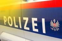 Ein Nahaufnahme der Seite eines Polizeiwagens mit dem Wort 'POLIZEI' und dem österreichischen Wappen auf einem blauen und roten Hintergrund.
