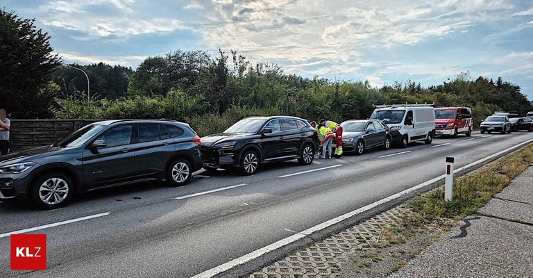 Ein Verkehrsunfall mit mehreren Autos und Rettungskräften am Straßenrand. Ein schwarzer SUV ist beschädigt, und ein weißer Lieferwagen ist geparkt.