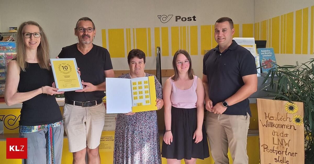 Eine Gruppe von vier Personen steht vor einer gelben Wand mit dem Wort Post. Der Mann auf der linken Seite hält ein Zertifikat mit der Nummer 10. Die Frau in der Mitte hält ein Buch. Die Frau auf der rechten Seite trägt eine Brille. Der Mann auf der rechten Seite trägt eine Uhr.