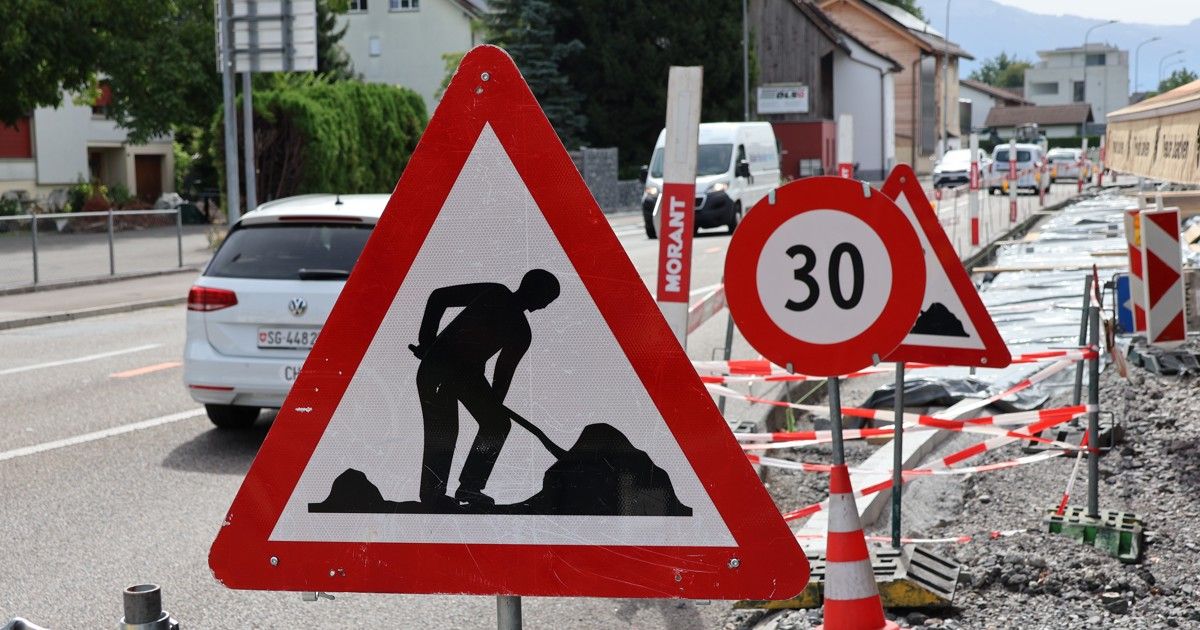 A road sign indicating roadwork ahead with a silhouette of a worker using a shovel. Nearby, a speed limit sign shows 30 km/h.