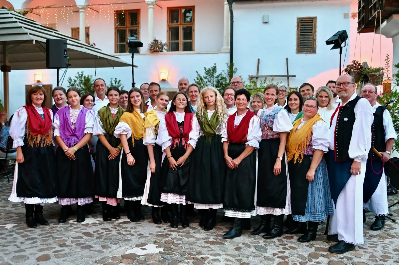 Eine Gruppe von Menschen in traditioneller Kleidung posiert für ein Foto vor einem Gebäude.