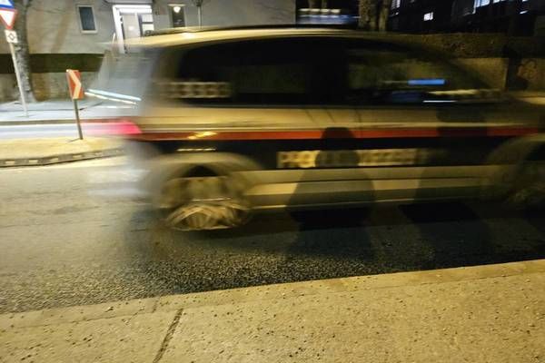 Eine verschwommene Aufnahme eines Fahrzeugs mit rotem Streifen, das nachts auf einer Straße fährt.