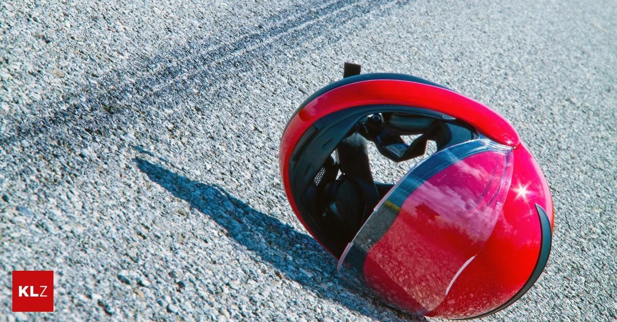 Ein roter Motorradhelm liegt auf dem Boden und zeigt Anzeichen eines kürzlichen Unfalls mit sichtbaren Kratzern und einem gebrochenen Visier.
