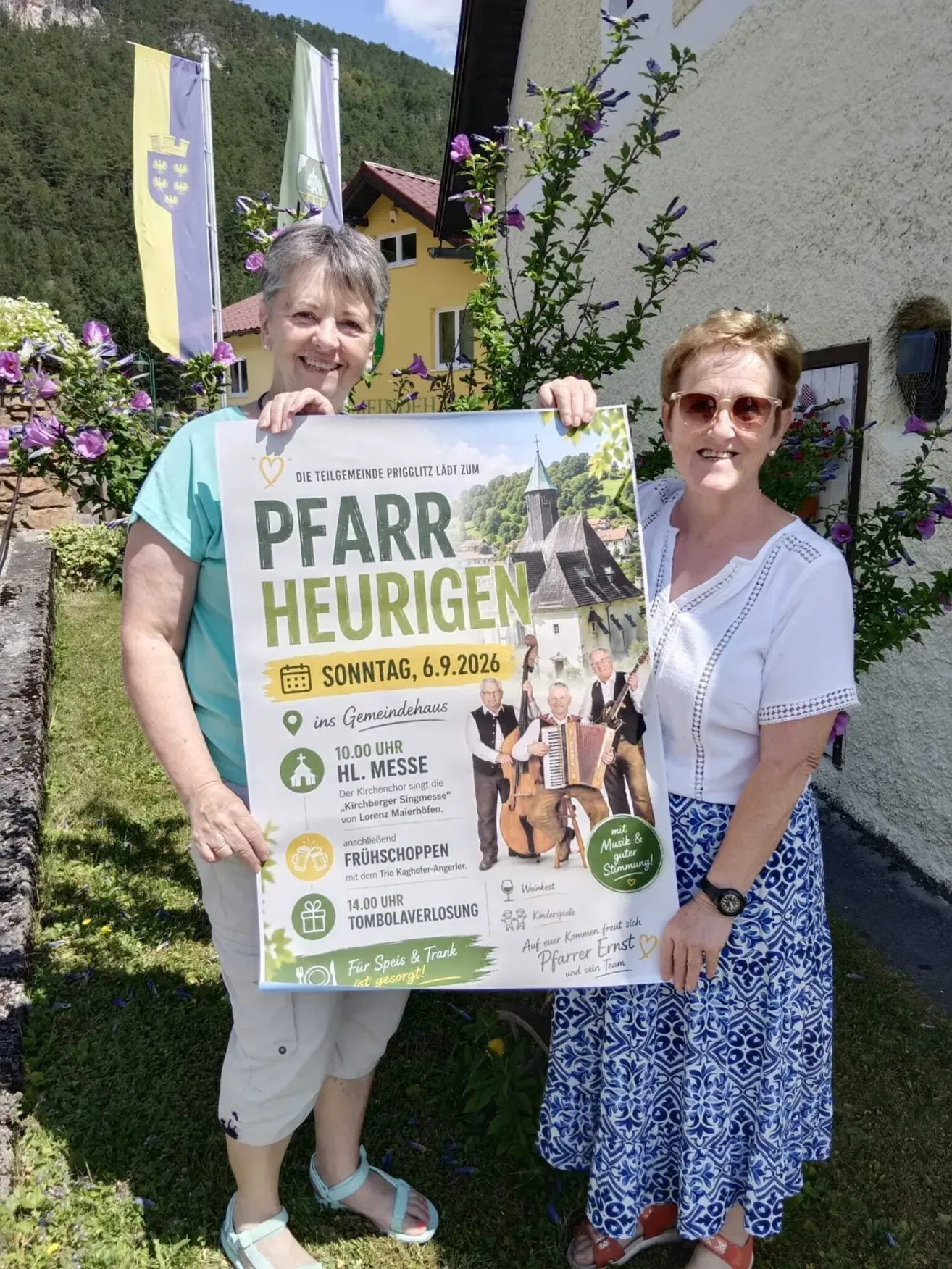 Two women hold a poster for an event at a community hall on Sunday, June 9, 2026. The poster features a photo of musicians playing instruments and a church in the background.