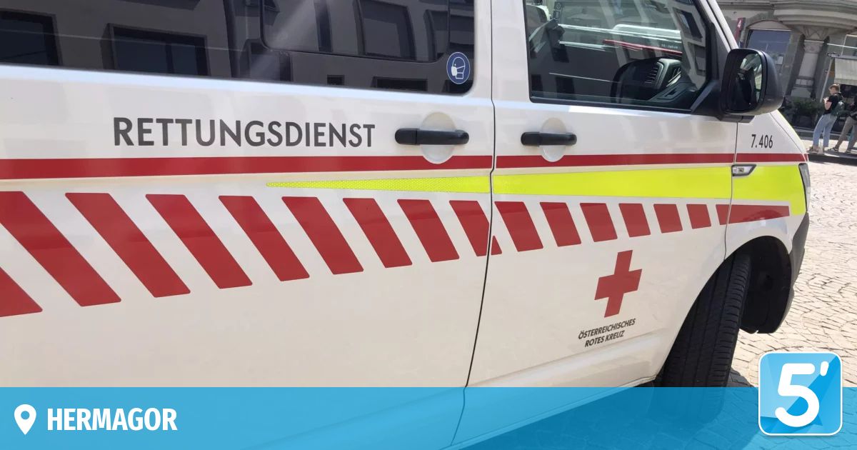 Nahaufnahme der Seite eines Rettungswagens mit 'Rettungsdienst' und rotem Kreuz-Symbol. Das Fahrzeug ist weiß mit roten und gelben Streifen.