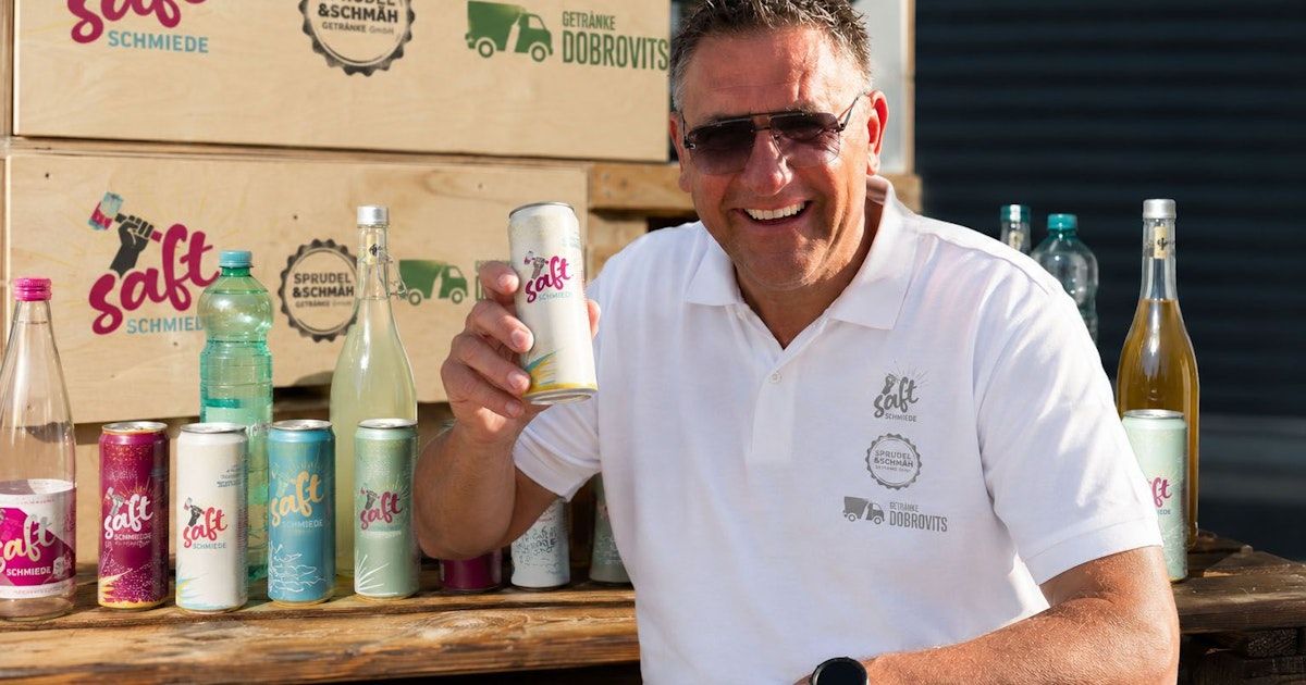 A man wearing sunglasses and a white polo shirt is holding a can of Salt beer. Behind him, there are several cans and bottles of Salt beer on a wooden table. In the background, there are wooden crates with the logo of the brand.