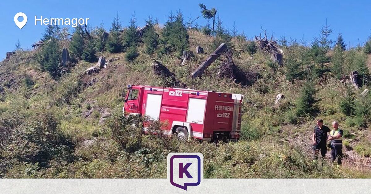 A red fire truck is parked on a steep hillside with a clear blue sky in the background. The truck is labeled 'Feuerwehr' and '122'.