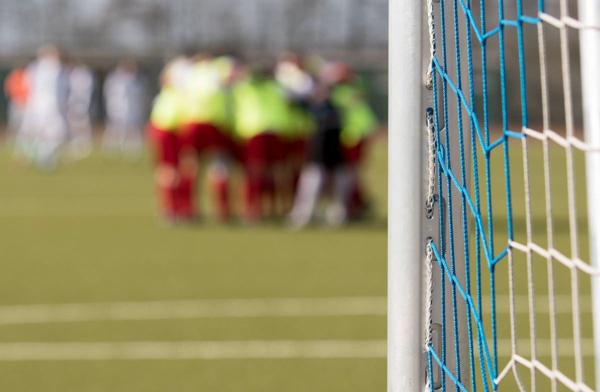 Ein verschwommenes Bild einer Fußballmannschaft in grünen und roten Trikots, die auf einem Feld versammelt sind.