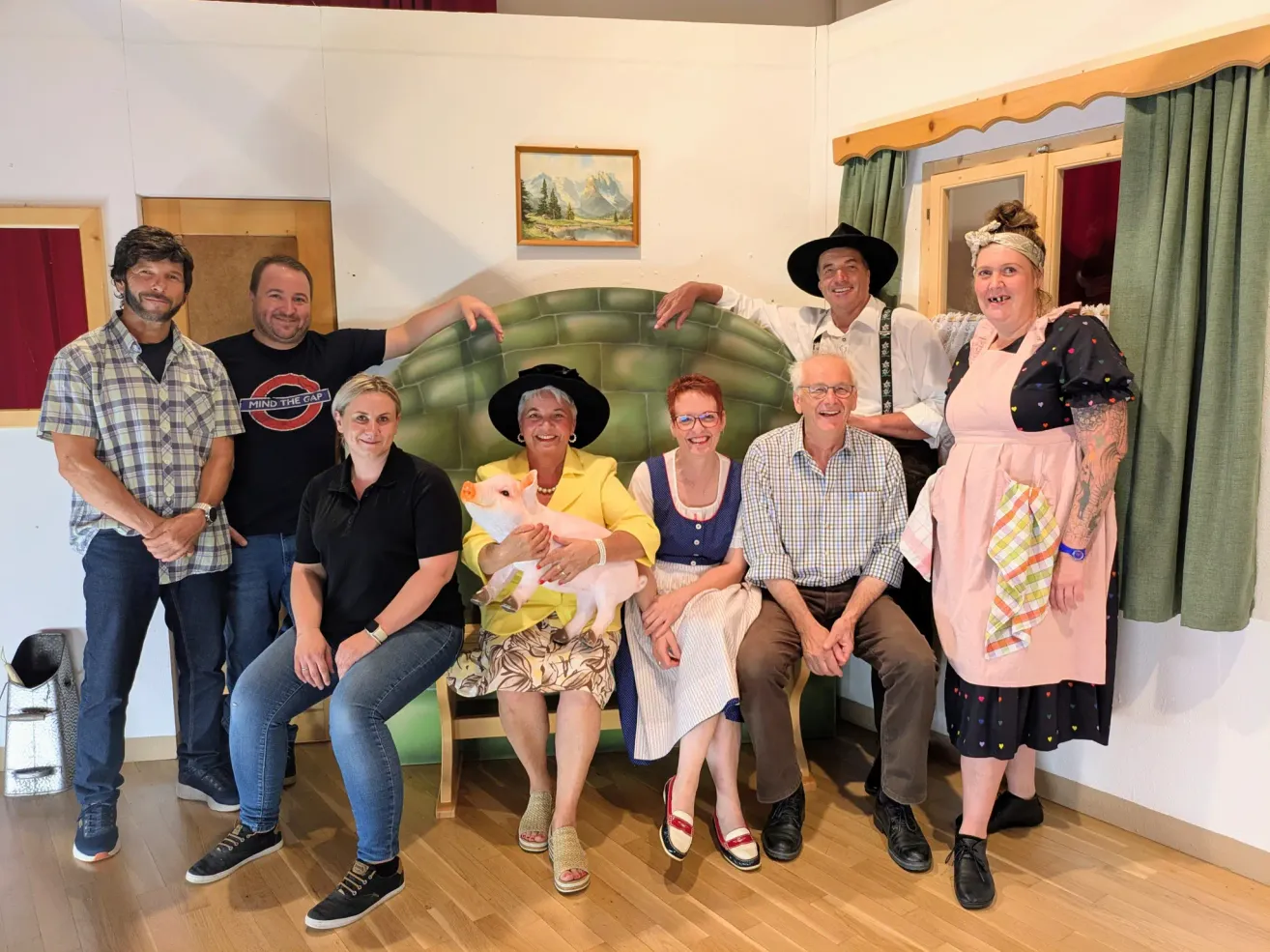 Eine Gruppe von Menschen posiert für ein Foto in einem Raum, eine Frau hält ein Schwein.