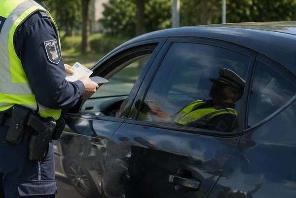 A police officer is checking a driver's documents at a roadside checkpoint.