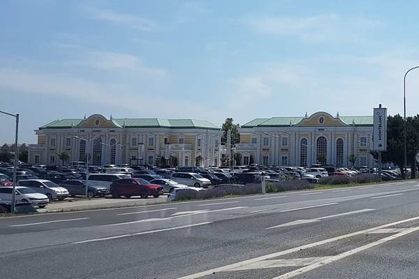 Ein großer Parkplatz mit vielen Autos vor einem großen Gebäude.