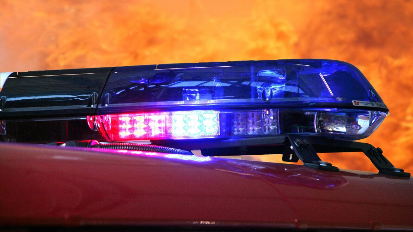 Nahaufnahme der roten und blauen Warnleuchten eines Polizeiwagens vor einem Sonnenuntergangshimmel.