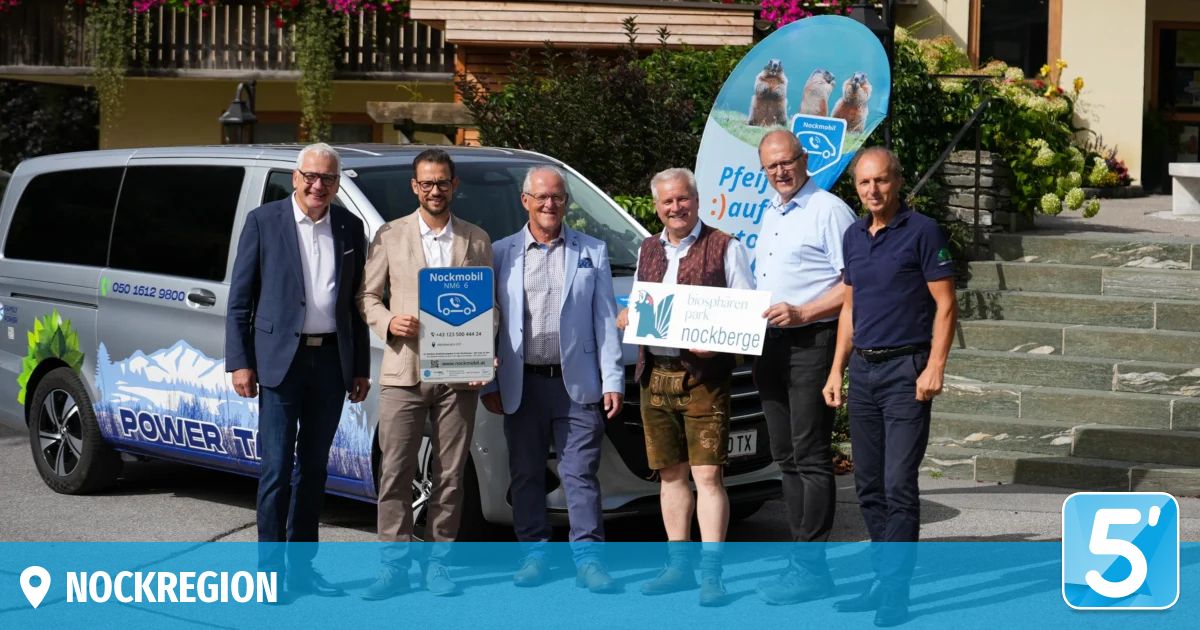Five men stand in front of a white van, holding signs. They are dressed formally and appear to be posing for a photo. Behind them is a banner with an image of groundhogs and the text 'Pfleg auf'.