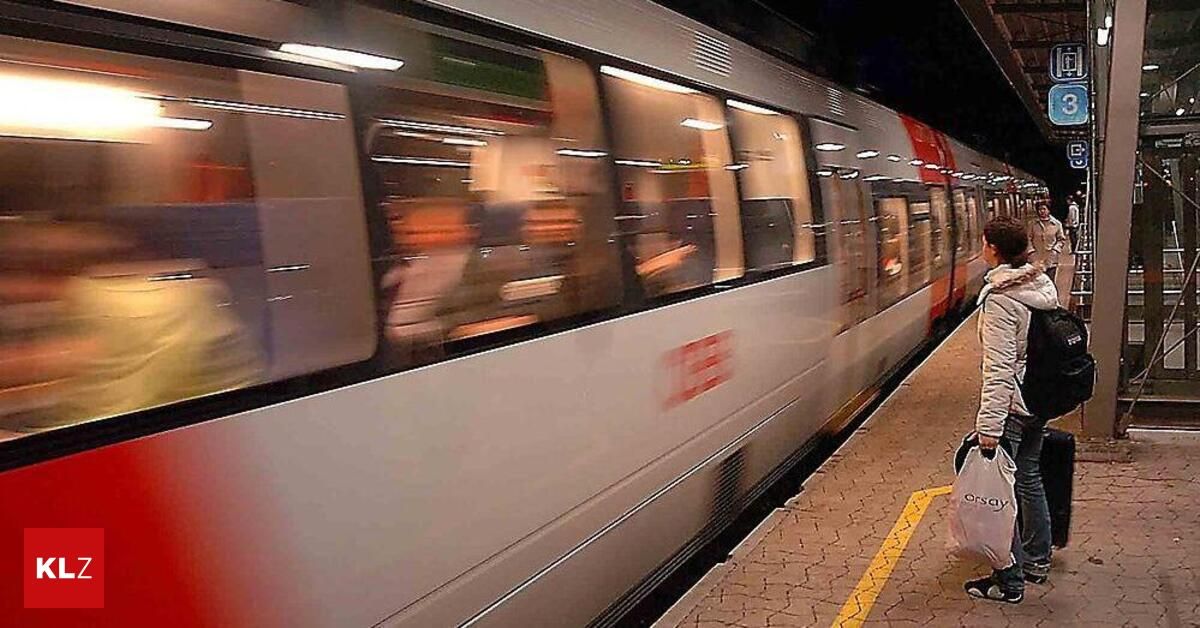 Ein verschwommenes Bild eines Zuges mit Passagieren im Inneren, der sich auf den Gleisen an einem Bahnhof bewegt.