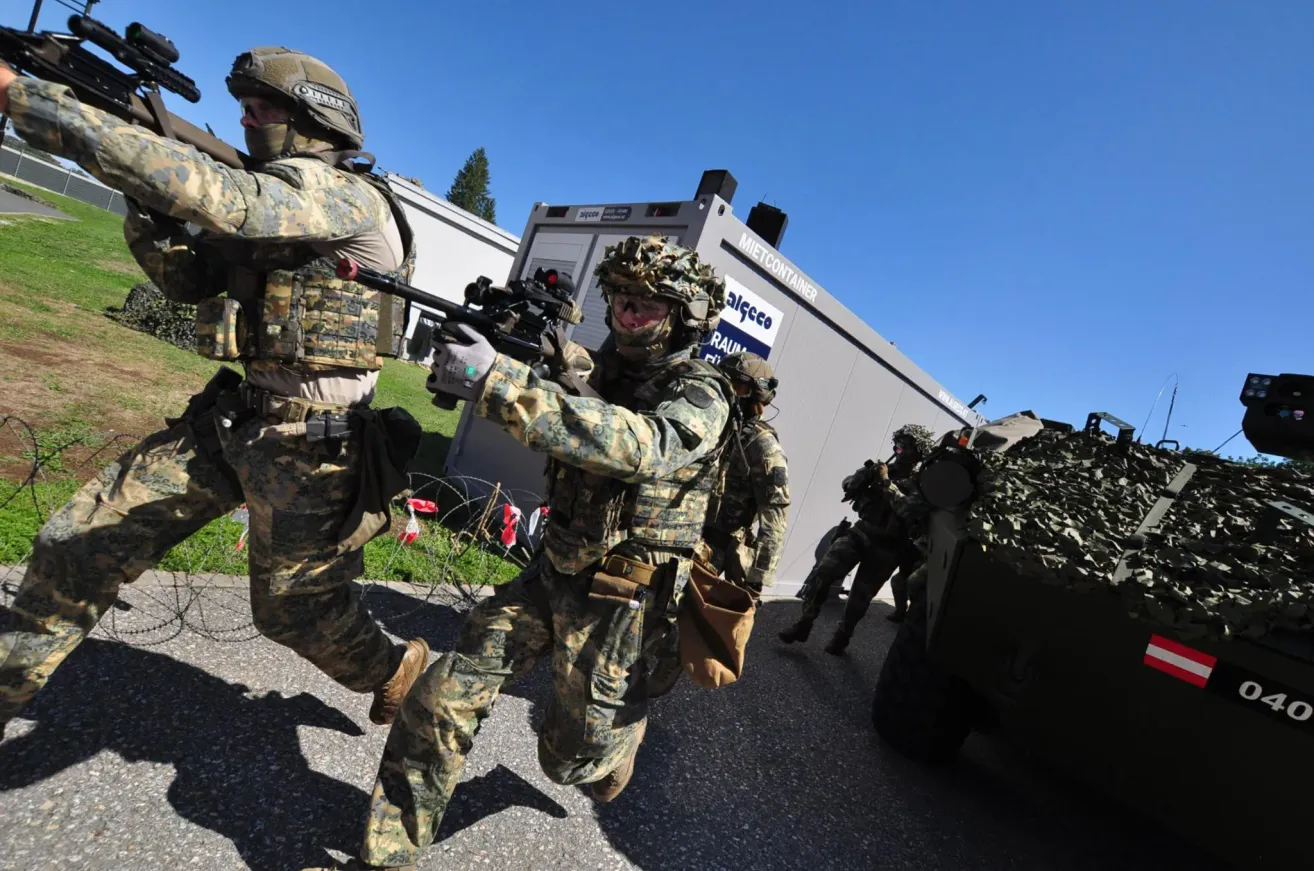 Soldaten in Tarnuniformen rennen und tragen Schusswaffen, möglicherweise während einer militärischen Übung.