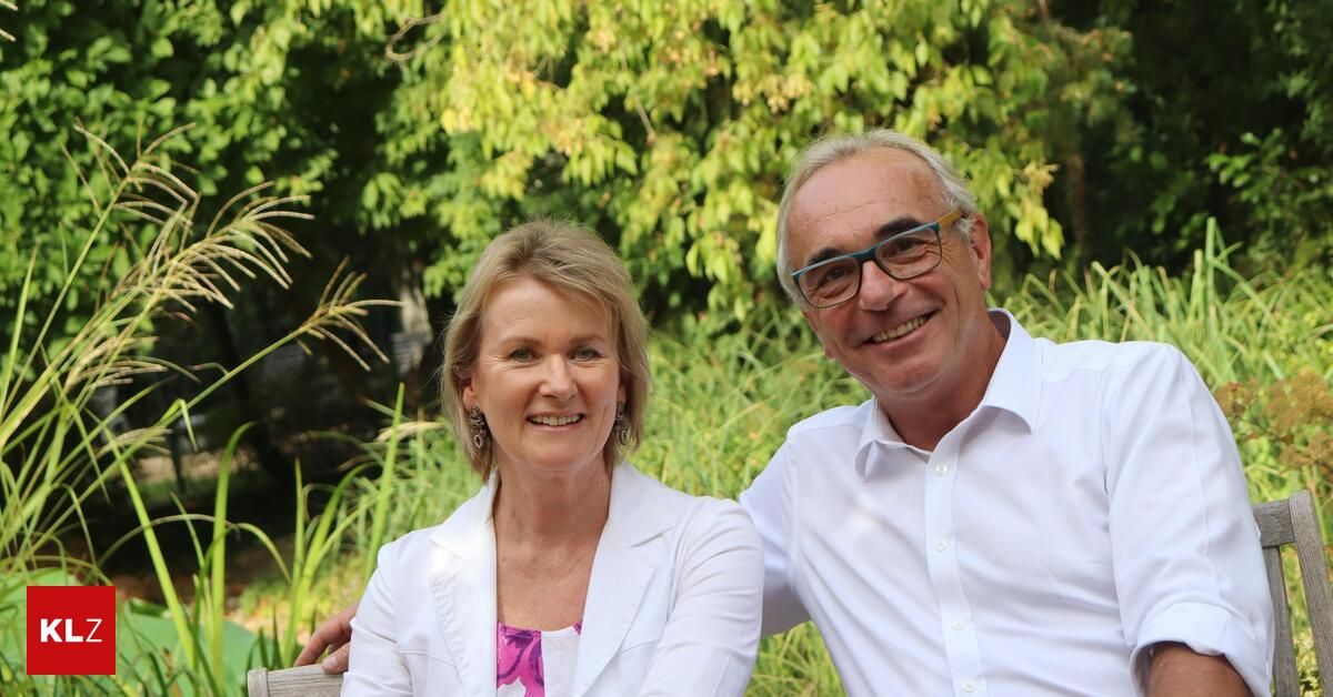 A man and a woman are smiling and posing for a photo in a garden.