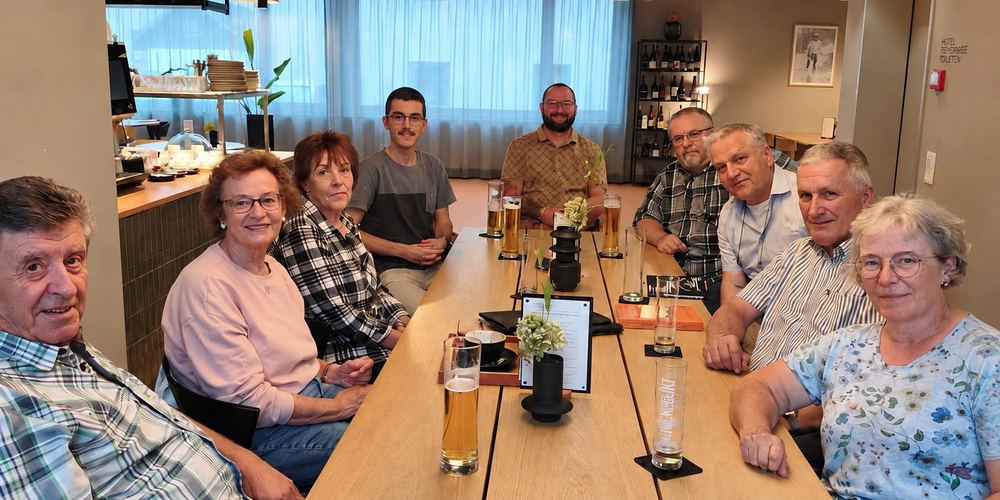 Eine Gruppe von Menschen sitzt um einen Tisch mit Biergläsern und posiert für ein Foto.