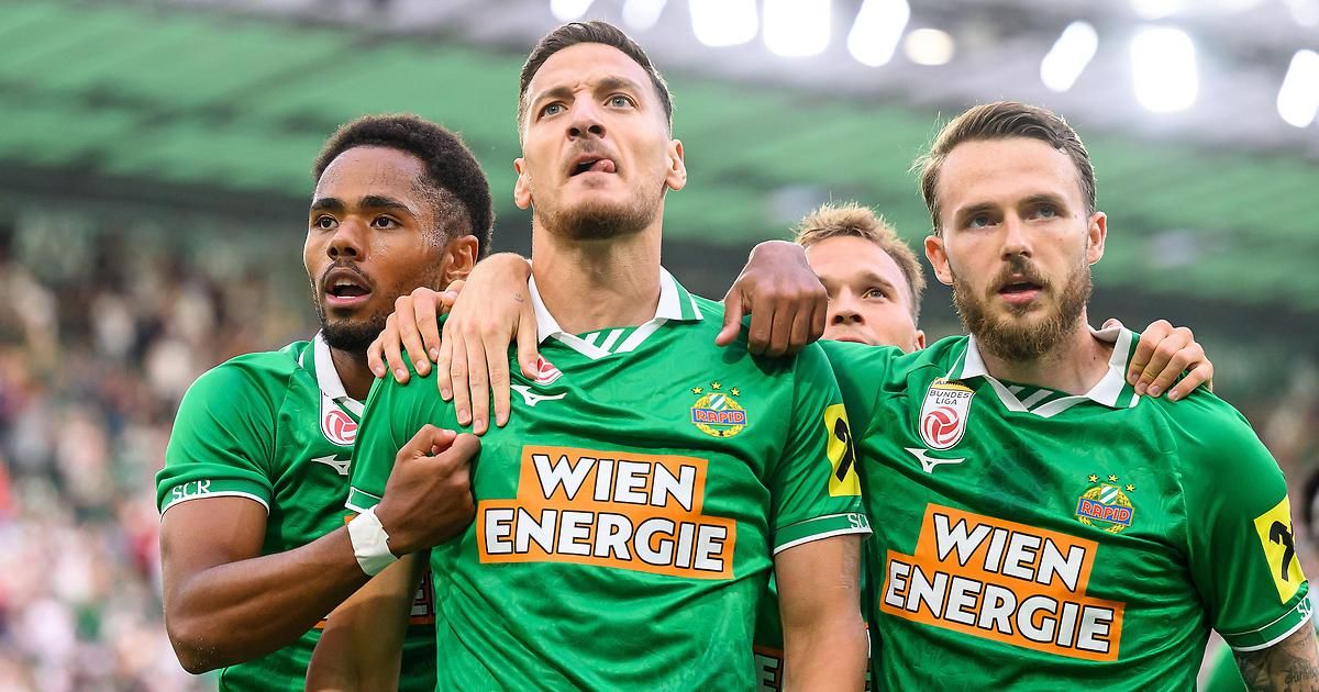 Eine Gruppe von Fußballspielern in grünen Trikots mit dem Wort 'Wien Energie' darauf feiert auf dem Spielfeld.