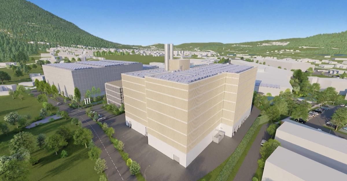 Luftaufnahme einer modernen Industrieanlage mit Solarpanelen auf dem Dach und einem großen Parkplatz davor.