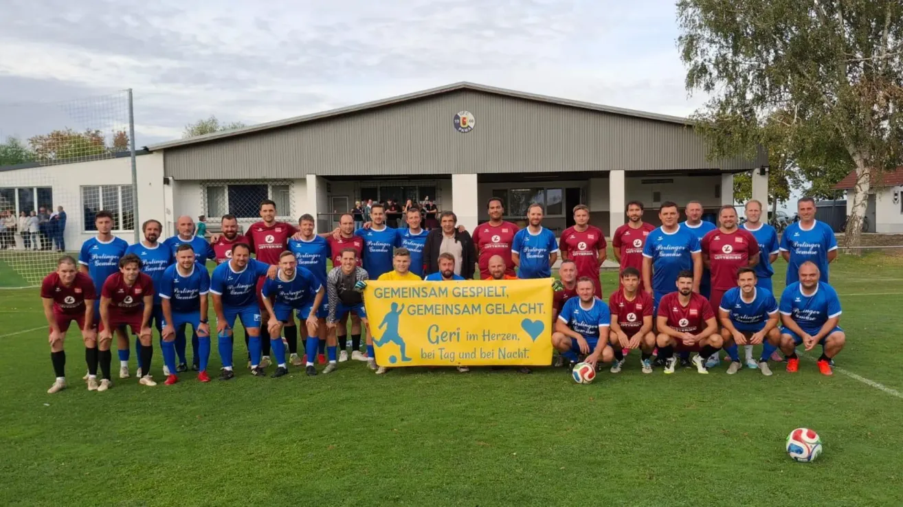 Eine Fußballmannschaft posiert für ein Foto vor einem Gebäude mit einem Banner, das Gemeinsam gespielt, gemeinsam gelacht. Bei Tag und bei Nacht. steht.