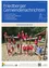 Eine Gruppe von Kindern in roten Shirts und Shorts spielt auf einem Spielplatz, während ein Mann in einem blauen Shirt zuschaut.