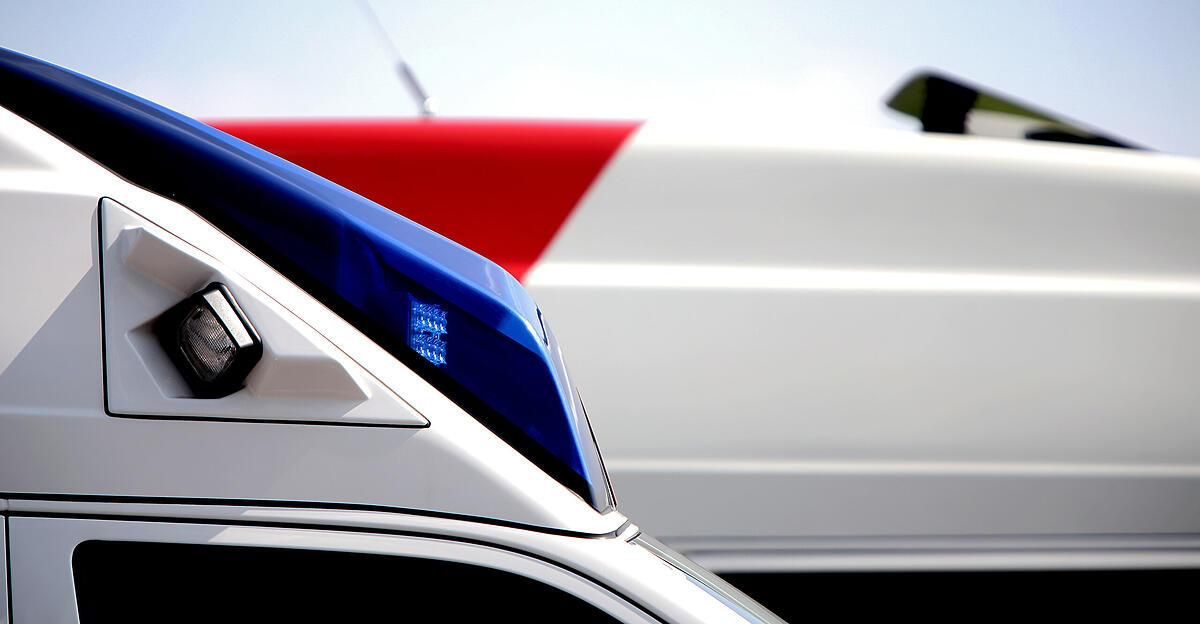 Nahaufnahme des vorderen Stoßfängers eines blau-weißen Autos mit blauem Licht.