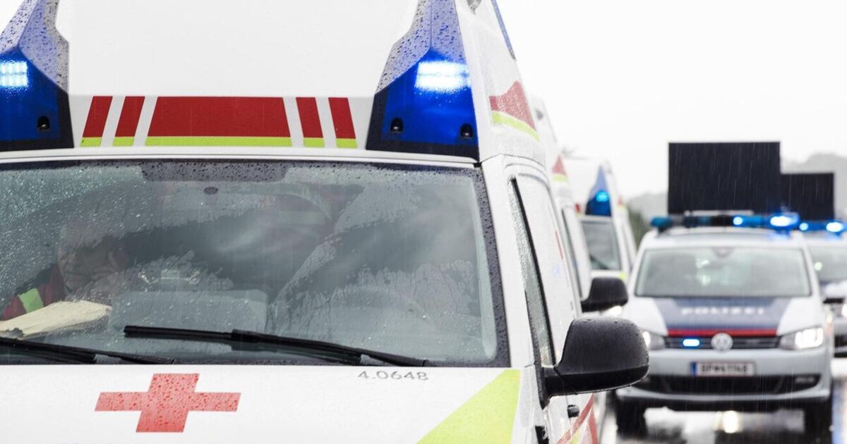 Ein Krankenwagen mit blinkenden blauen Lichtern steht am Straßenrand.