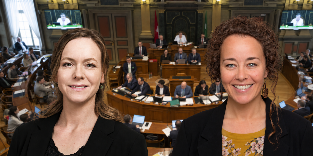 Zwei Frauen stehen vor einem verschwommenen Hintergrund einer Parlamentssitzung und lächeln in die Kamera.